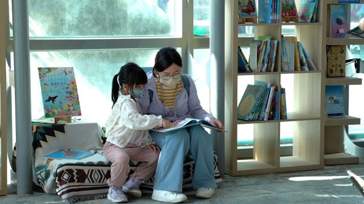 圖1於銅雕大廳圖書區，家長帶著孩童閱讀有興趣的海洋書籍
